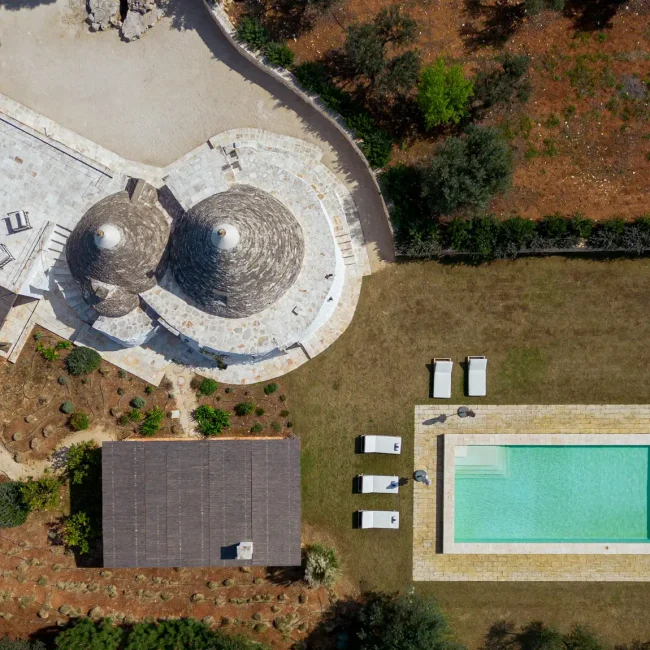 Trullo Petrarolo stone cottage with two conical roofs beside its private pool