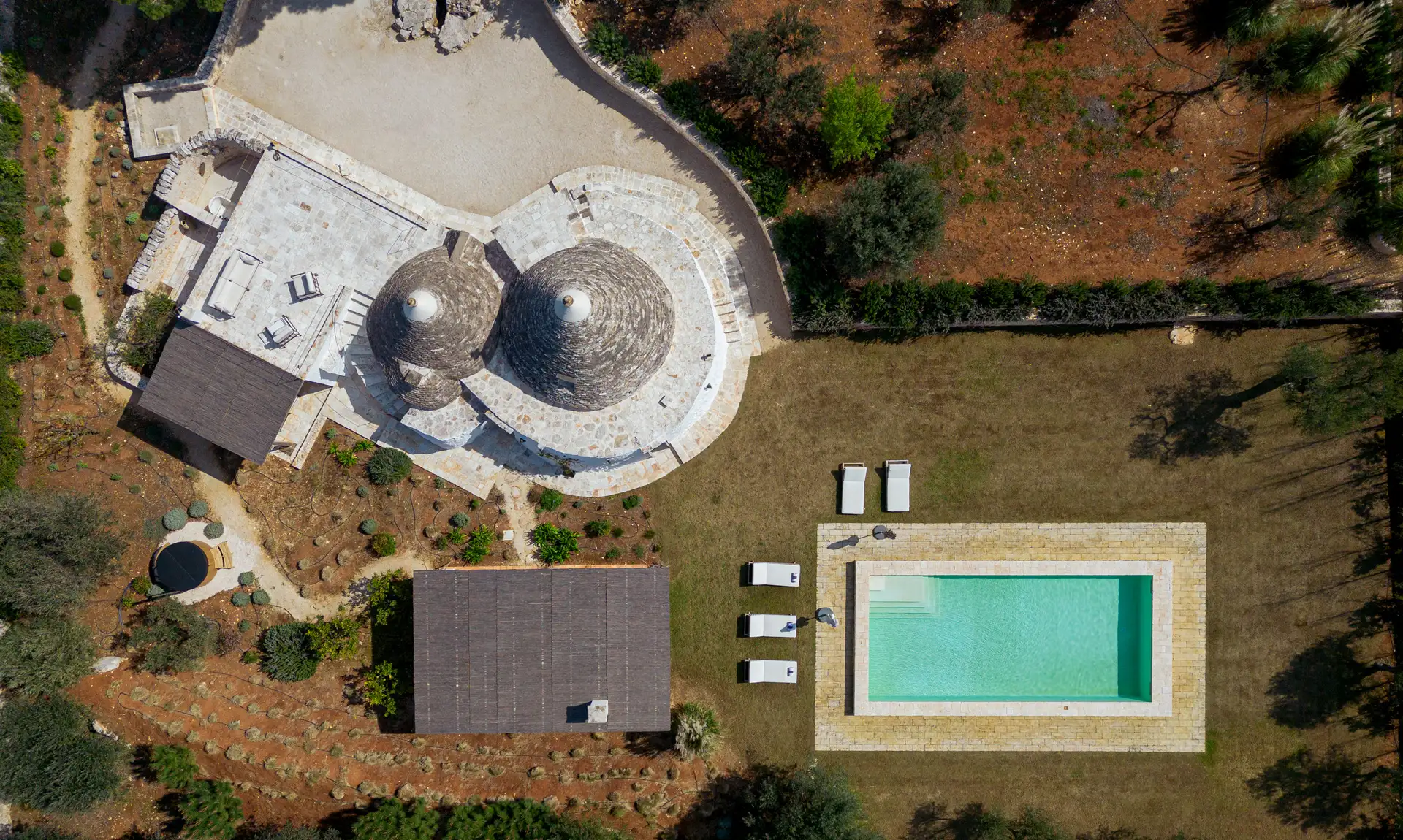 Trullo Petrarolo stone cottage with two conical roofs beside its private pool