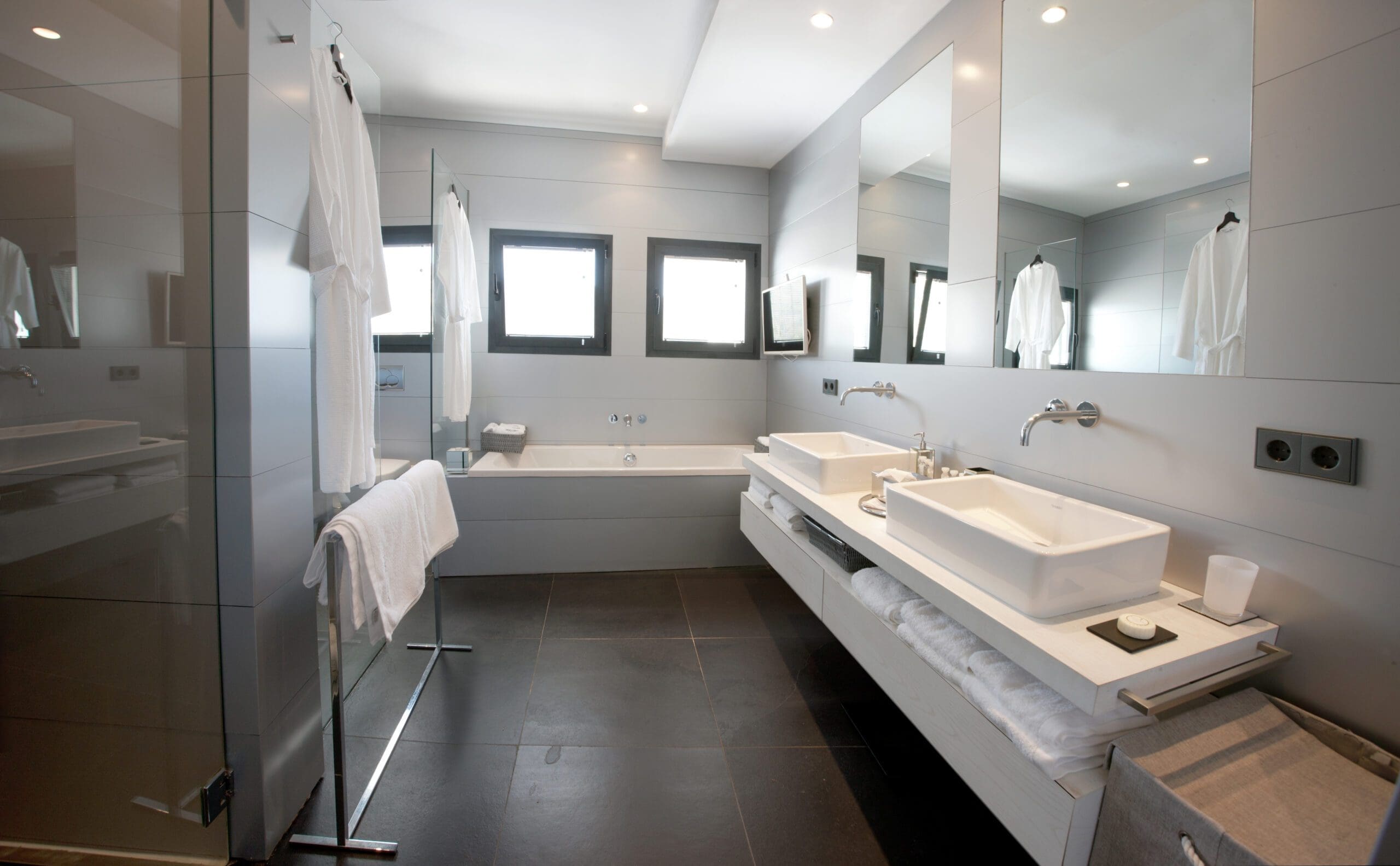 Tagomago bathroom with a bathtub, twin basins and a wide mirror