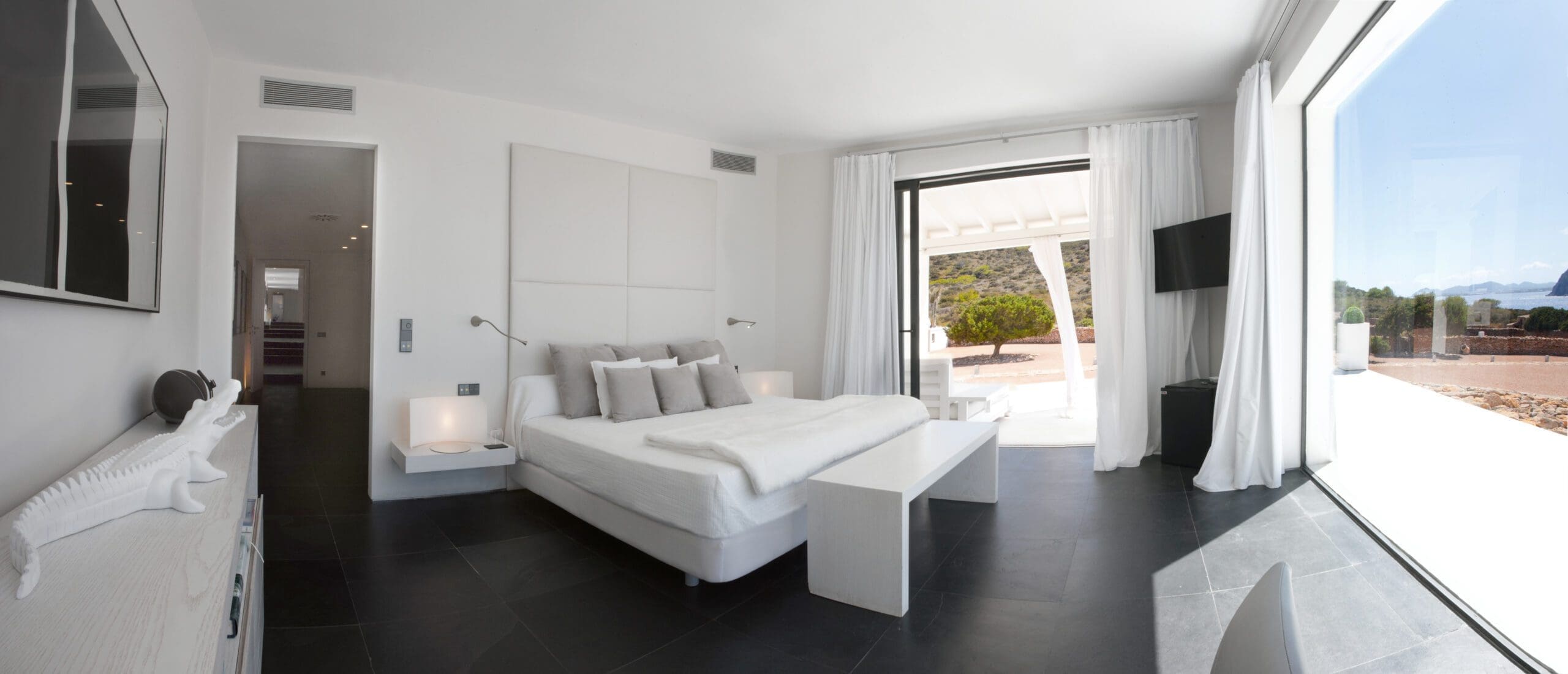Tagomago bedroom with sliding doors opening towards the villa pool terrace