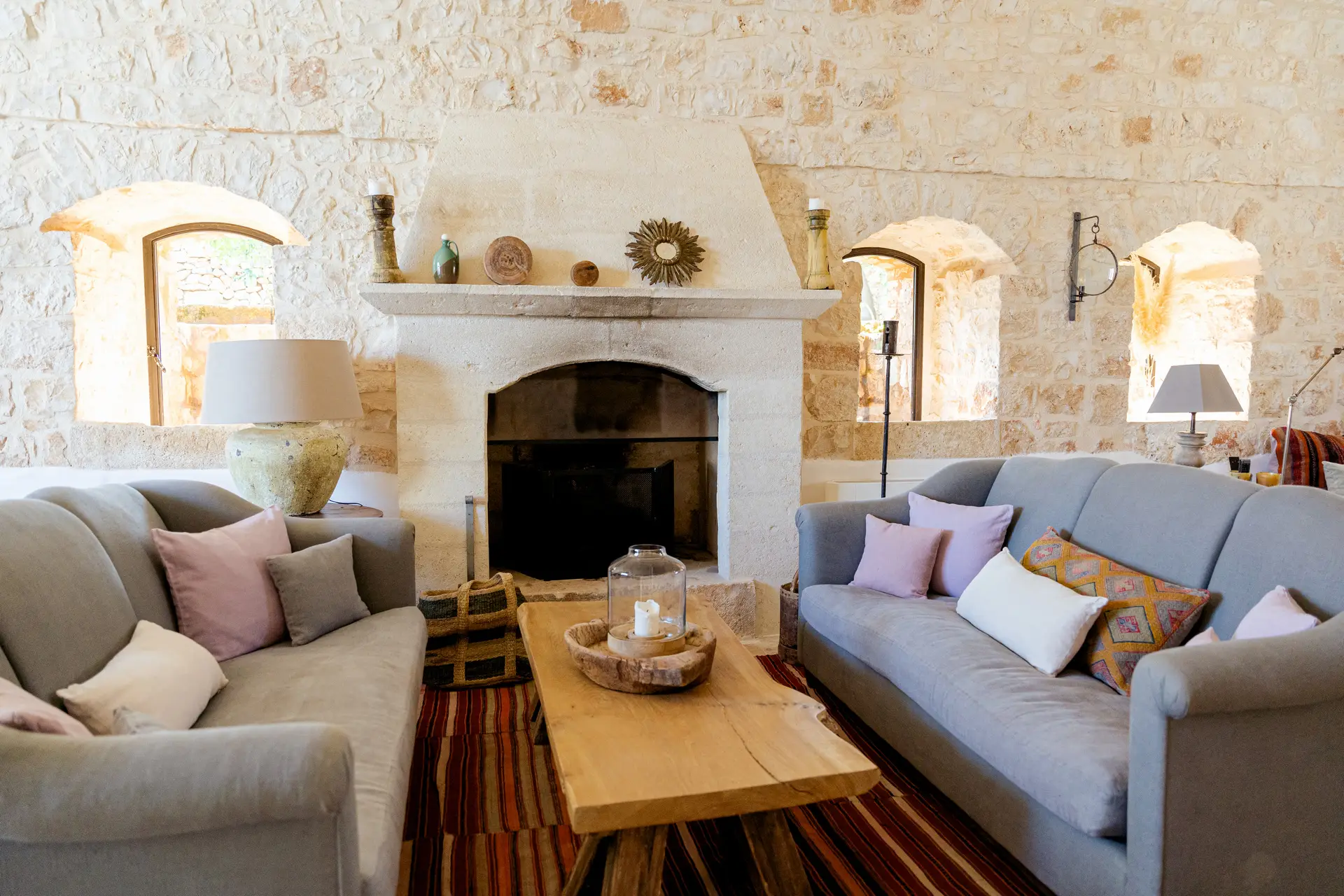 Stone fireplace and sofas around a wooden coffee table in a Masseria Petrarolo living room