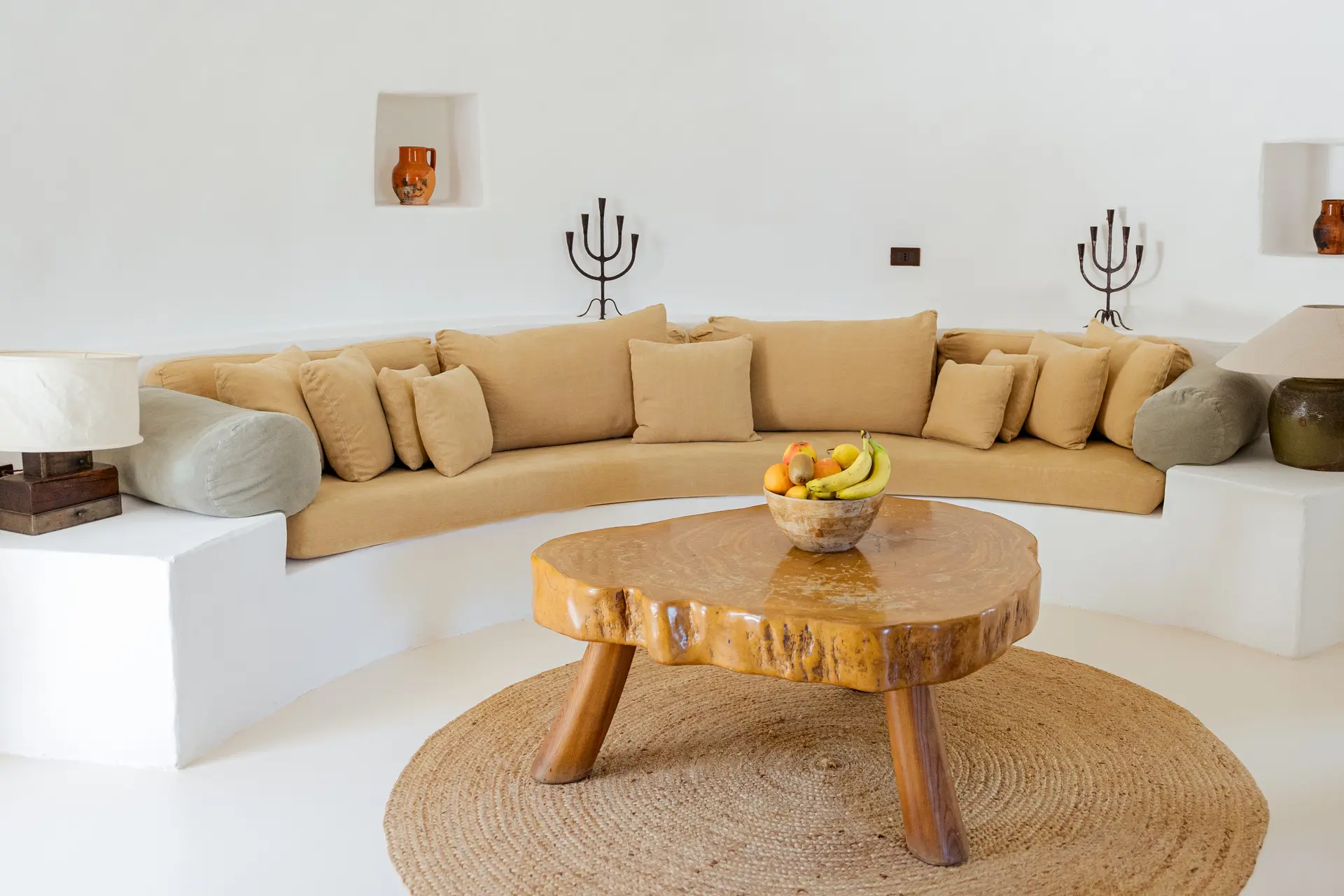 Curved sofa and a round wooden coffee table in the white living room at Trullo Petrarolo